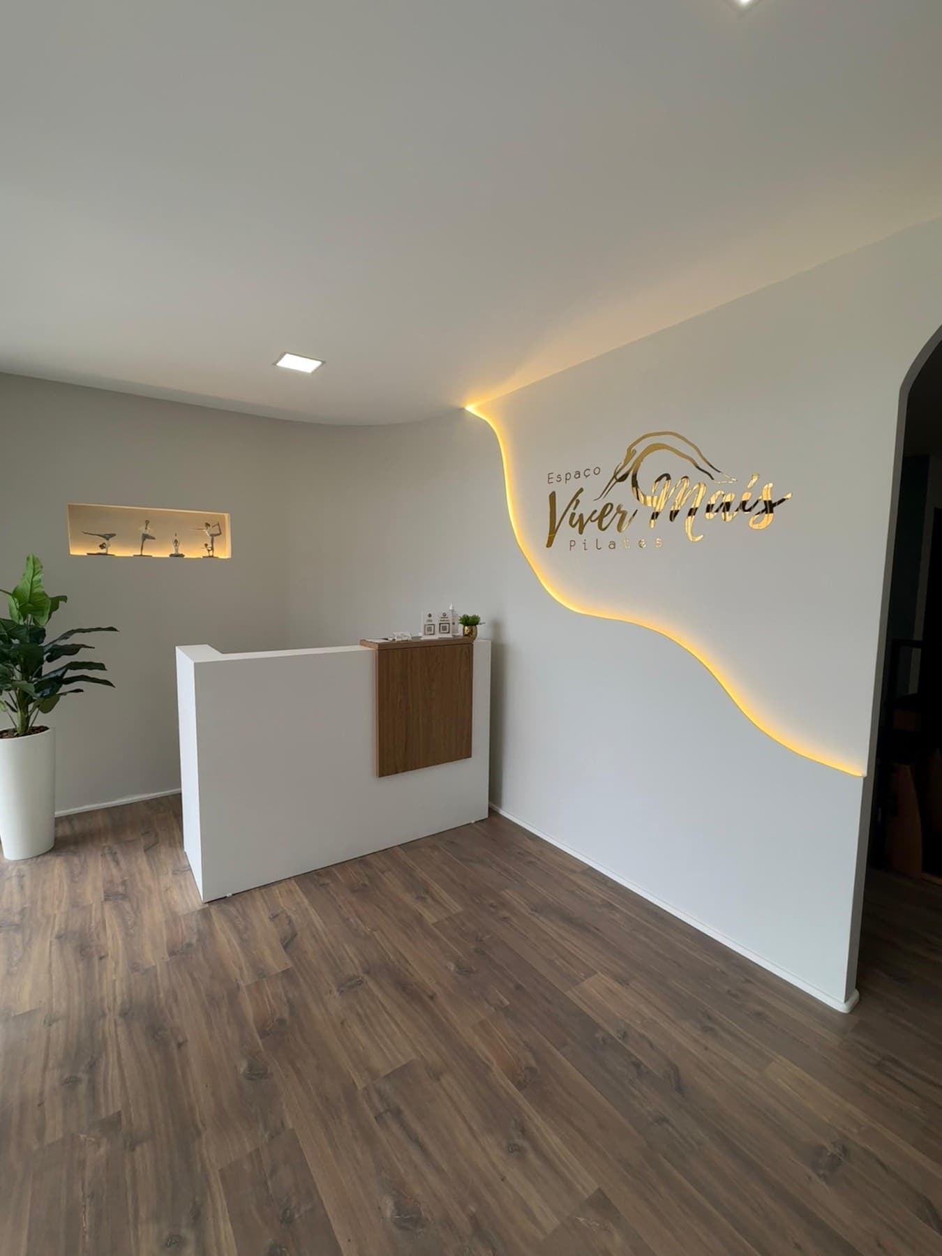 Recepção do Espaço Viver Mais Pilates com o logo iluminado na parede